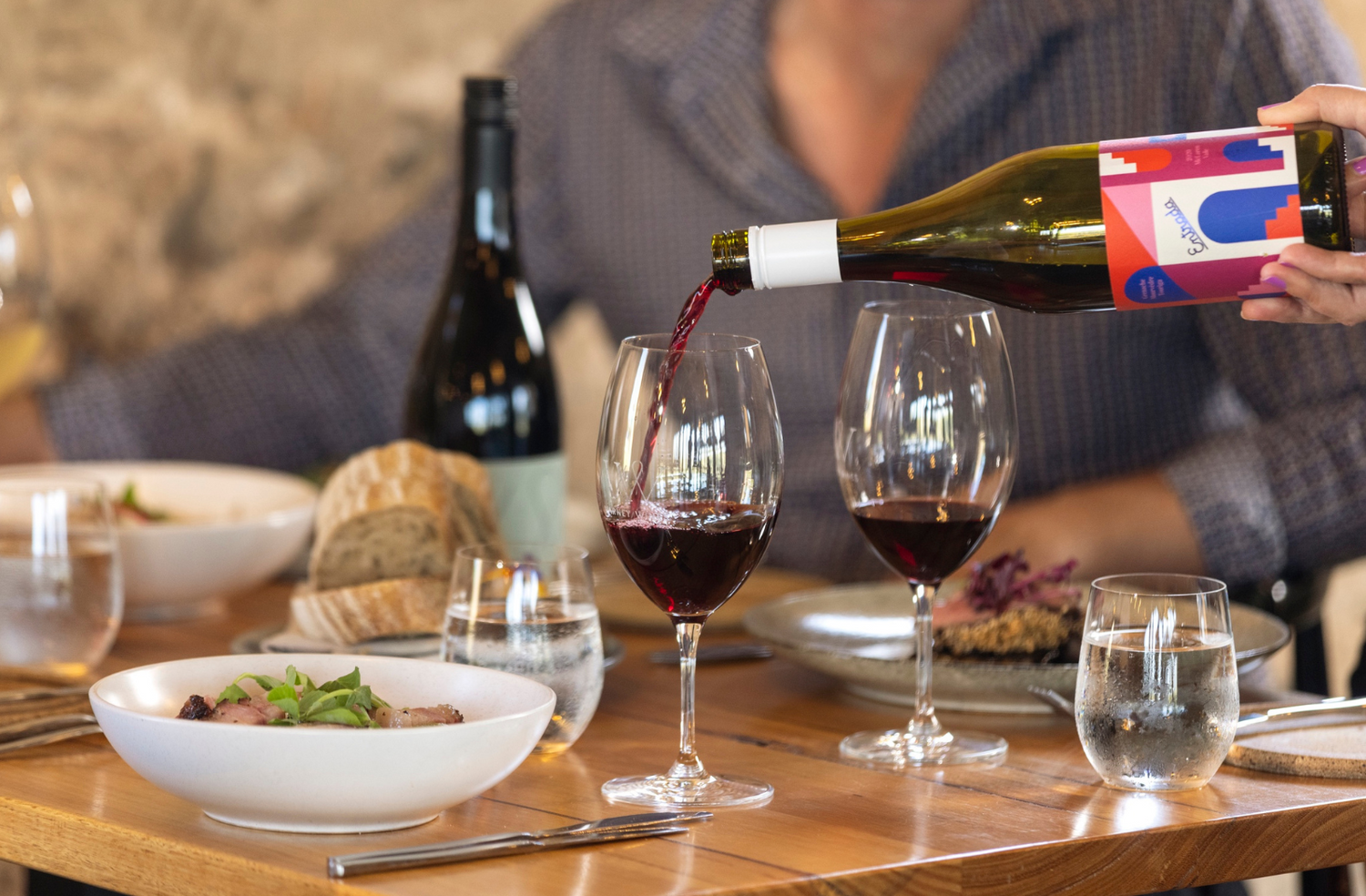 Varney Wines 'Entrada' GMT being poured into a glass at a table set with food, crockery and cutlery.