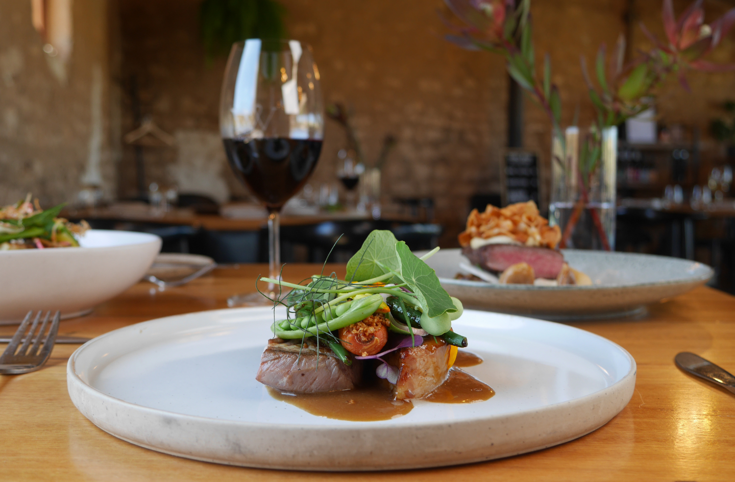 A glass of Varney Wines Mencia served on a table with a lovely duck dish.