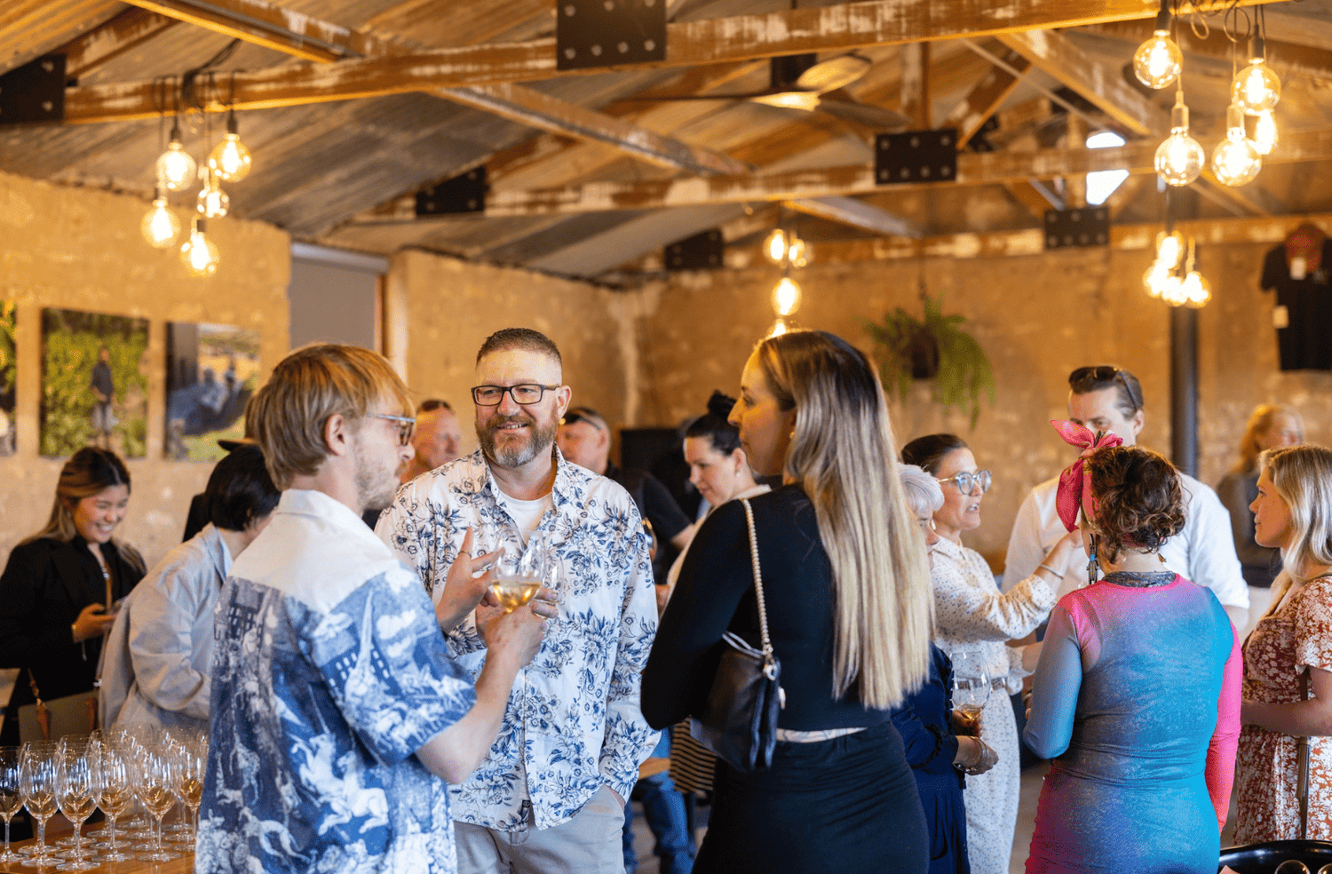 Group of guests enjoying an event at the Varney Wines tasting room. People are smiling, talking and sipping wine.