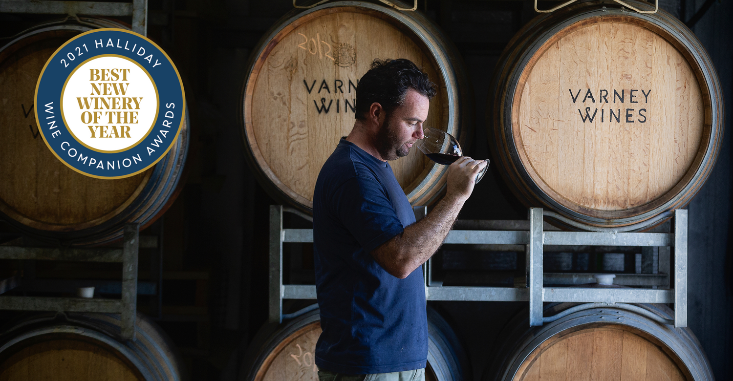 Alan Varney standing in the winery smelling Varney Wines. Featured logo on image is Halliday Wine Companion for the Best New Winery of the Year 2021