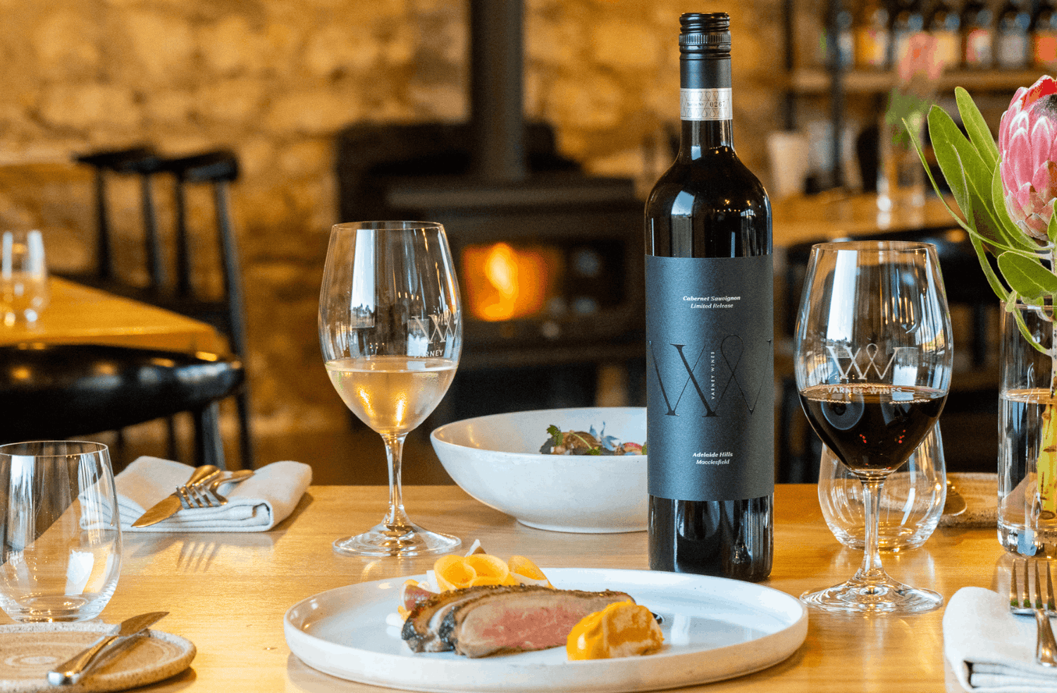 Varney Wines Cabernet Sauvignon on table with food and wine and table settings.