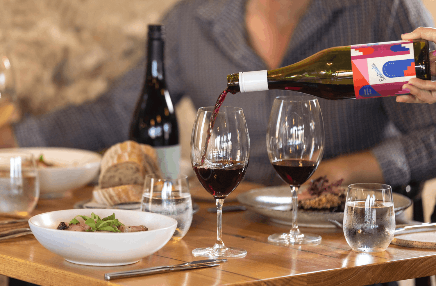Varney Wines 'Entrada' GMT being poured into a glass at a table set with food, crockery and cutlery.