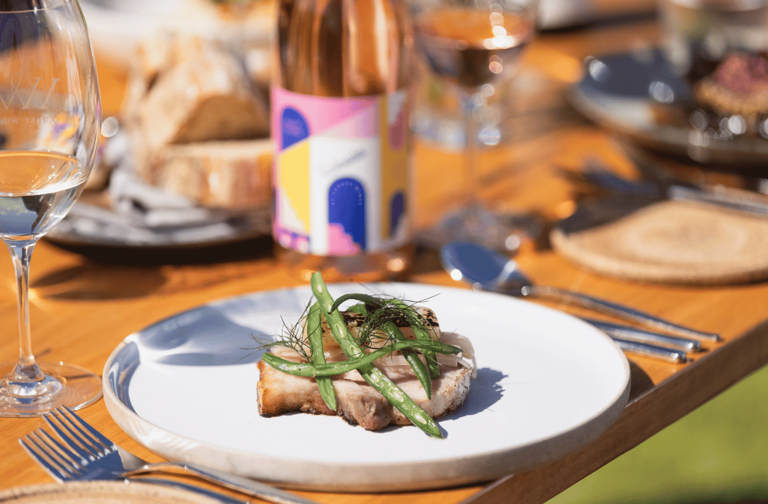 Plated dish of pork with Asian greens served on a table with Varney Wines 'Entrada' Rosé of Grenache.